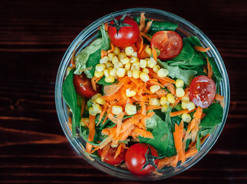 salad filled with tomatoes, corn, carrots and spinach