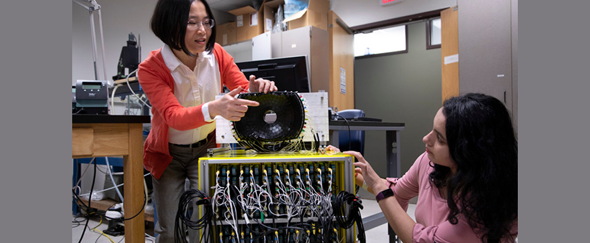 An Asian American woman is pointing to a sensor array and showing it to another woman