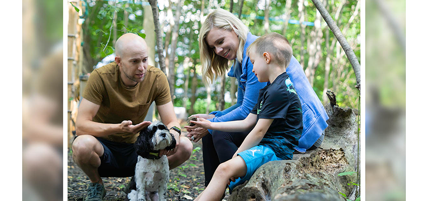 Leah with her husband, son and their dog chat in the woods